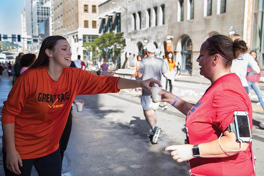 Freshman cinema production major and honors student volunteer Sarah Campbell hands out cups of water to Great Race runners as they near the end of the race. 