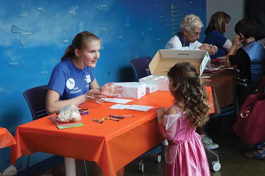 Volunteer Dakota Marcin helps young visitors make crafts during the Owl-O-Ween event at the National Aviary here in Pittsburgh