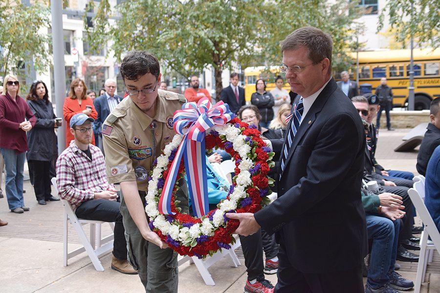 Tim Grebeck, sophomore education major and Eagle Scout, helps Professor Eric Stennett, Director of EDD Program at Point Park, carry a wreath to a stand by the waterfall in Village Park during a ceremony for Veteran’s Day on Friday. 