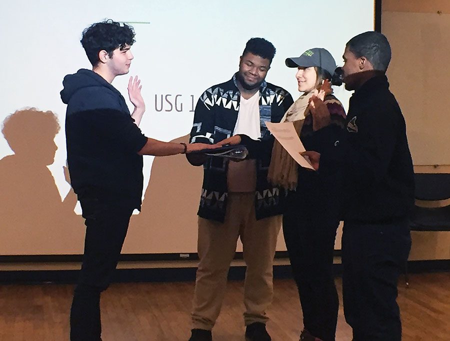 United Student Government President Blaine King, far right assisted by Parliamentarian Charles Murria, second from the left, swears in sophomore broadcasting major Samiar Nefzi and senior sports, arts and entertainment management major Priscilla Nevarez into student government. 