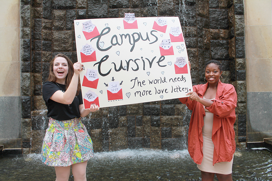 Campus Cursive: The World Needs More Love Letters President Chloe Jakiela and Vice President Vania Arthur brandish a poster publicizing the new club. 