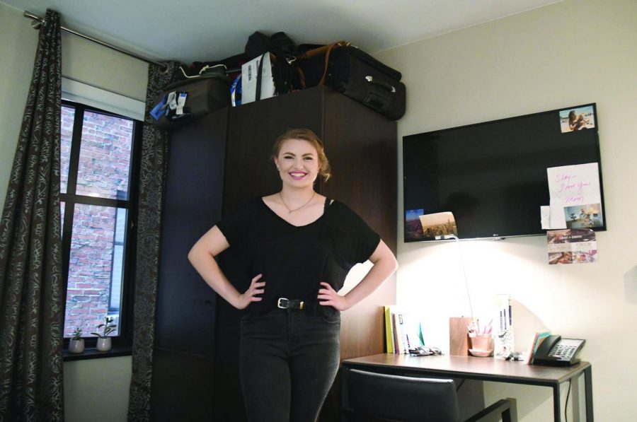 Shay McWeeney, sophomore acting major, poses in her hotel room at Distrikt Hotel. Her suitcases can be found packed to capacity on top of her bureau. McWeeney has made her room her own personalized space, and has decorated her desk and television with pictures to resemble a dorm.