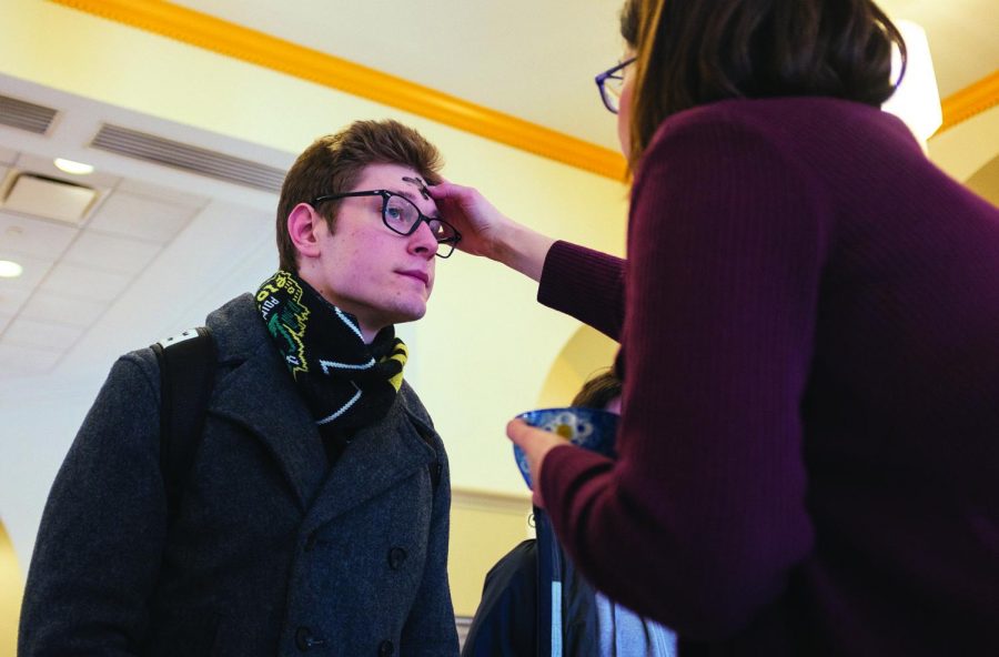 Nick Poprocky, senior public relations major, receives ashes for Ash Wednesday, the start of Lent, in the Lawrence Hall lobby from Pastor Jennifer McCurry.