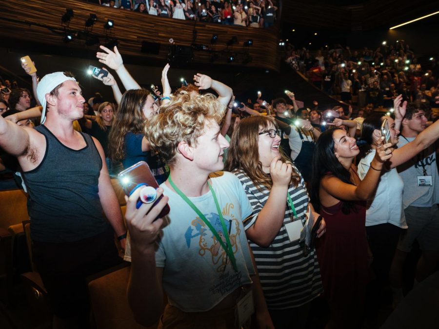 Incoming freshmen engage with a Pioneer Experience event by flashing their phone flashlights in the Pittsburgh Playhouse.