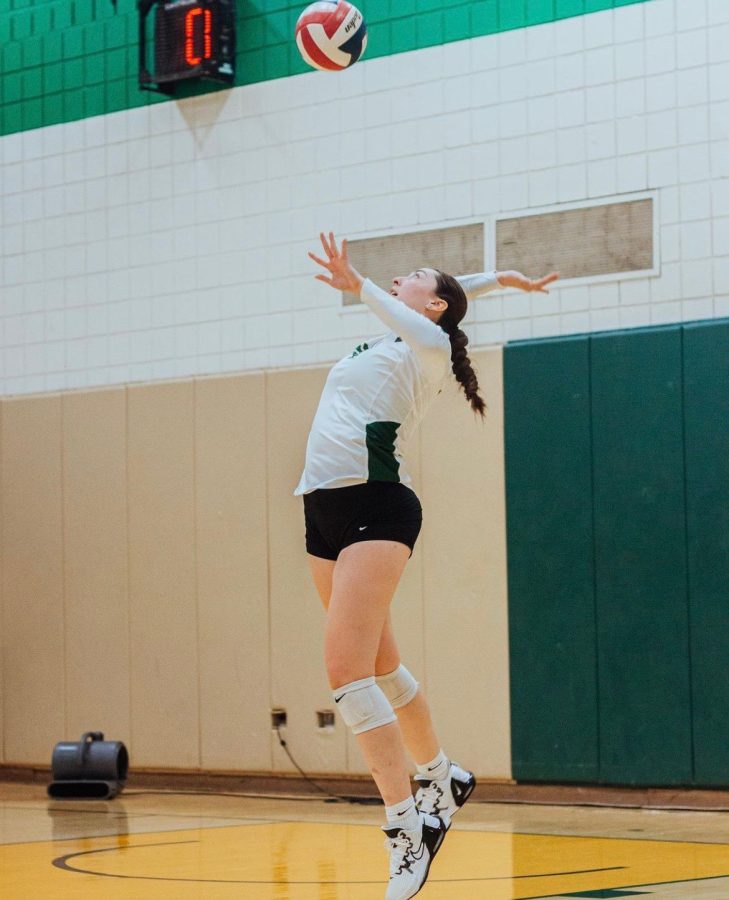 Kassandra Tejeda tosses the volleyball into the air, getting ready to serve the ball.