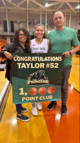 Taylor Rinn holds the 1,000 point banner with her parents, Shawnna (Left) and Michael (right).
