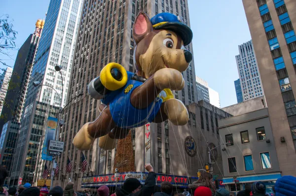 A Paw Patrol balloon flies high in the sky  in front of Radio City Music Hall.