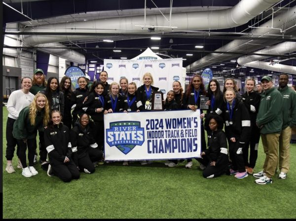 The womens team showing off their championship banner after winning conferences