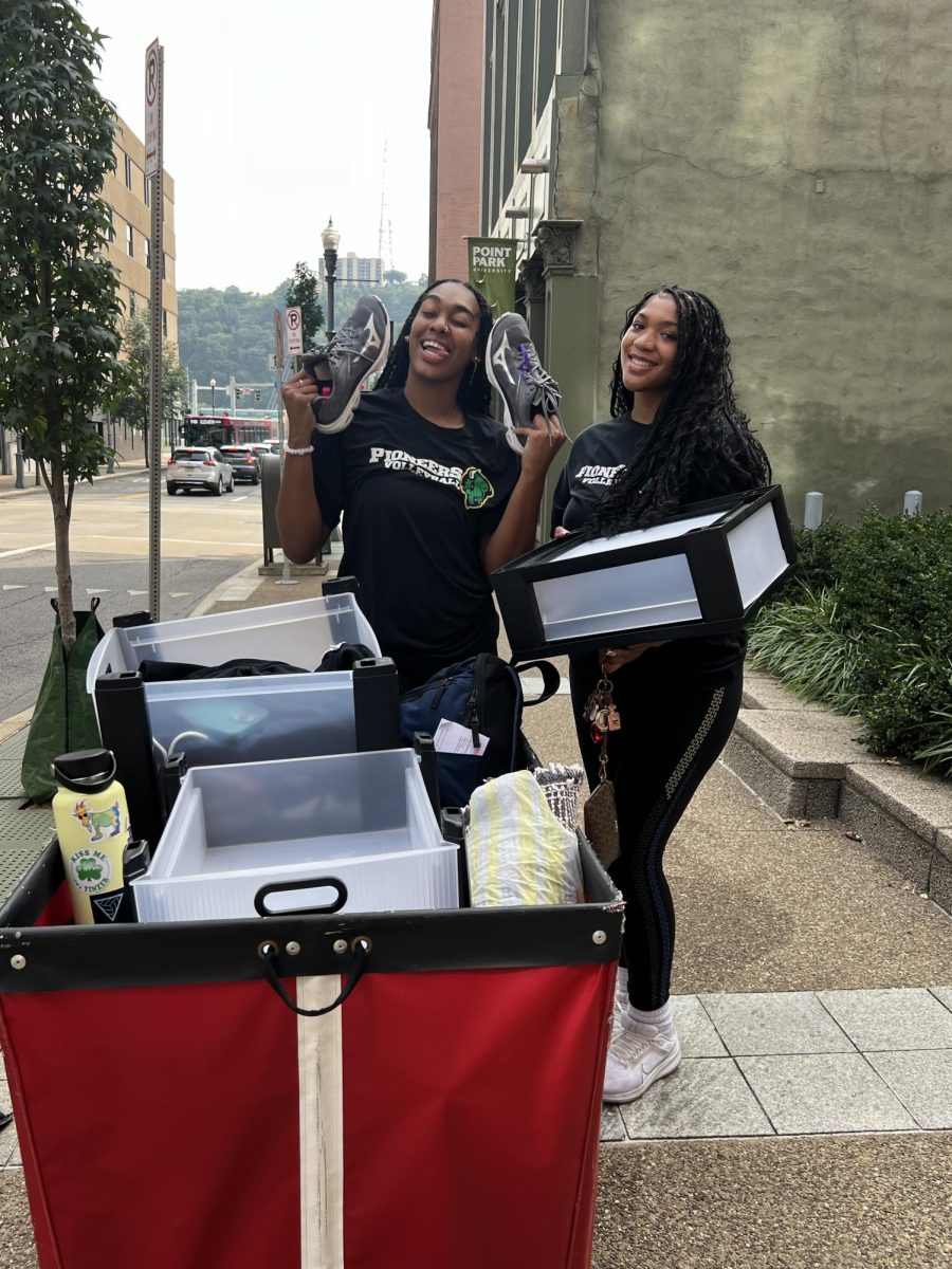 Brooke Wilson, sophomore, and Mariah Perez, senior, push red bins to their dorm during move-in.