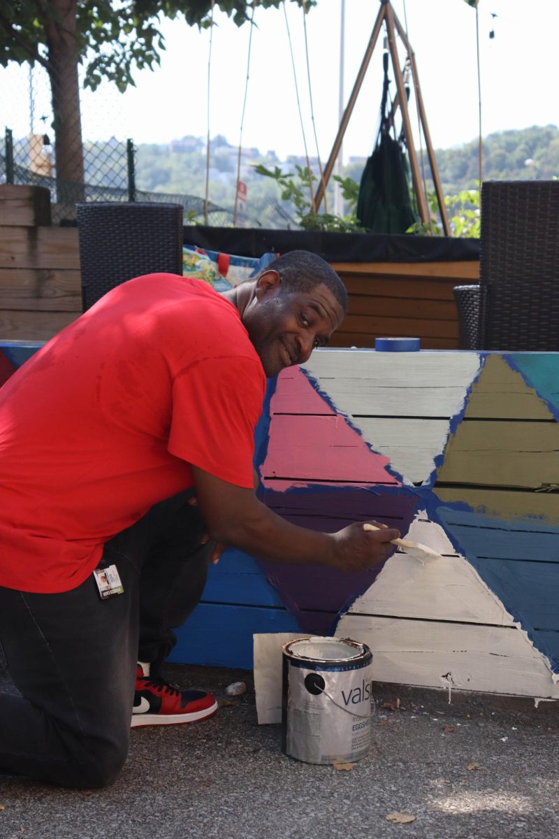 Shepherd "Shep" Fourgson, a first-year non-traditional student, paints a mural at the new community garden.