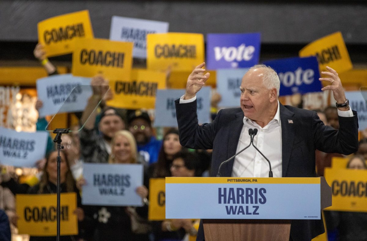 Governor Tim Walz of Minnesota speaks to rallygoers at Acrisure Stadium in front of a backdrop of supporters.