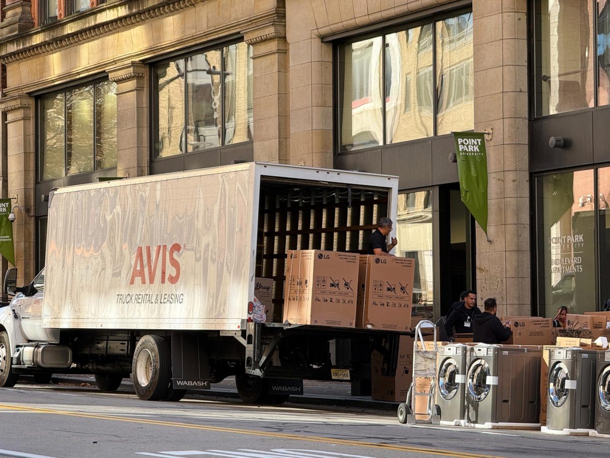 Workers with Fowler Laundry Services unload washers and dryers off a truck.