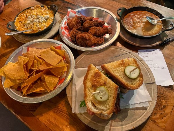 (Left to right) Spicy chicken dip, salted tortilla chips, fried chicken, spoonbread and a BLT sandwich are set onto a table at The Eagle. 