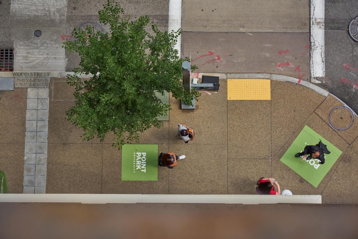 Students walk on the sidewalk of Wood Street, which has had sidewalk clings placed down to identify parts of campus since Picklesburgh in 2024.