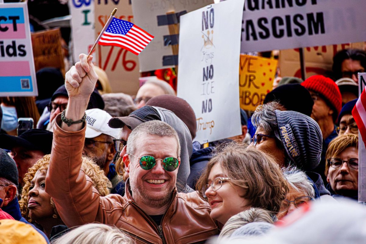 Demonstrators at the "No Kings" rally in downtown Pittsburgh wave flags and hold signs on Saturday.
